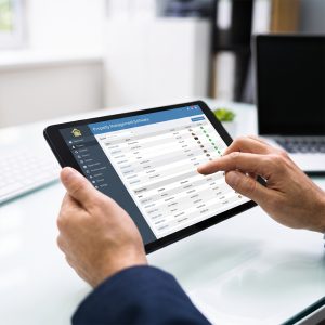 Hands using property management software on a digital tablet in a professional office.