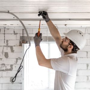 Electrician installing ceiling electrical wiring.